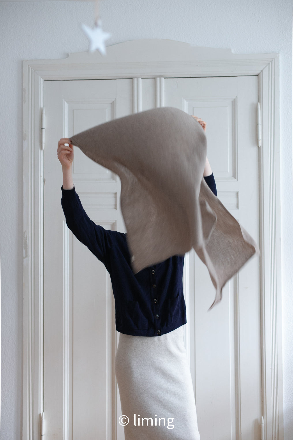 Model throwing a taupe color cashmere scarf